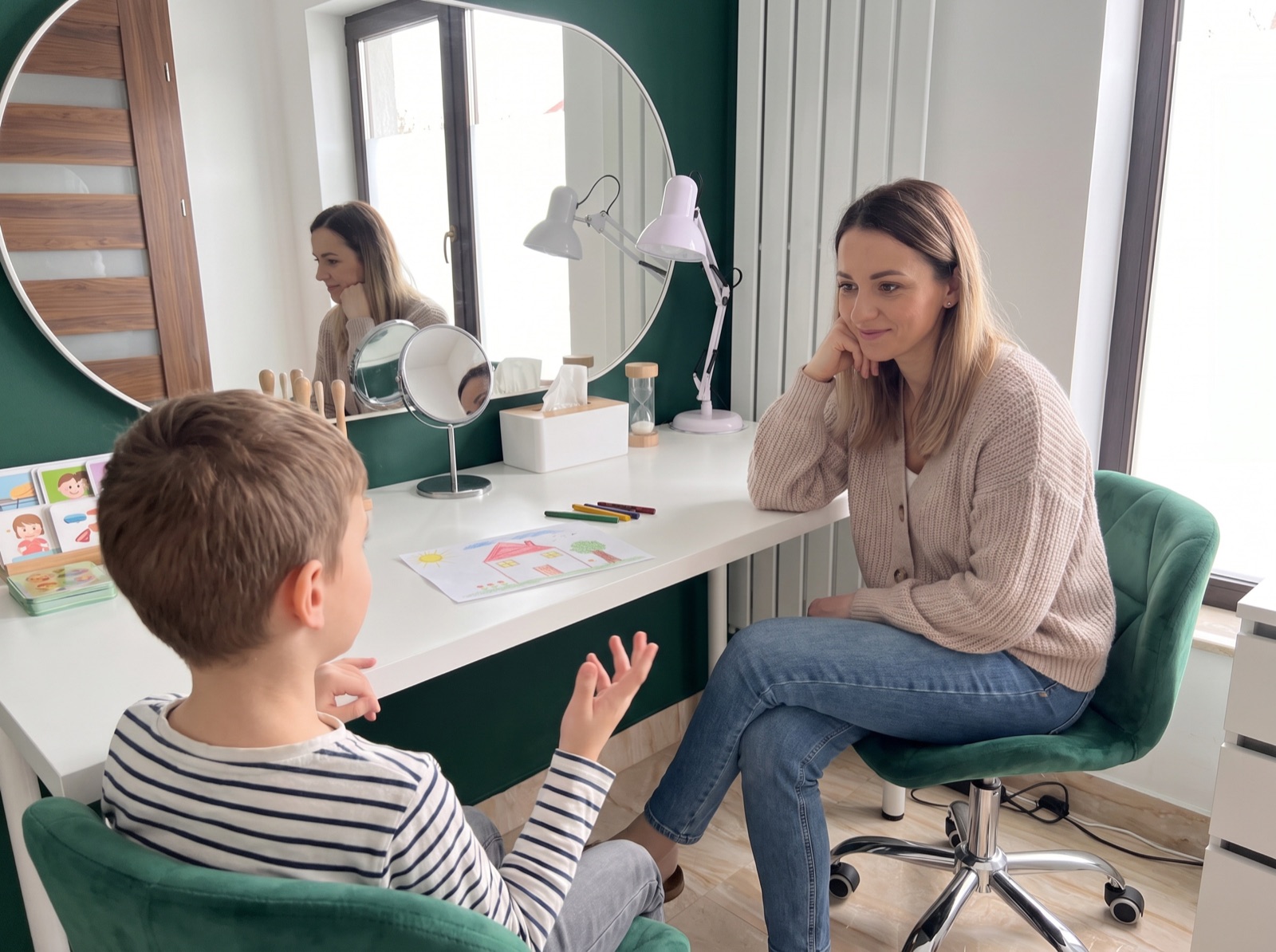 Psycholożka rozmawia z chłopcem podczas wizyty w Mandroya Senses - na biurku rysunek dziecka i kredki